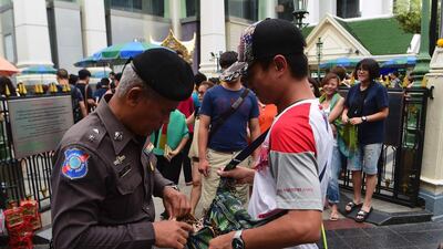 A policeman searches a visitor's bag at the Erawan Shrine in the centre of Bangkok yesterday as authorities increase security following a new string of bomb attacks in Thailand. Munir Uz Zaman / AFP