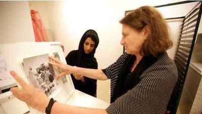 Salma al Mari, left, a student at Zayed Univerisity and Susan Mesieles put the finishing touches to a new exhibition about the Emirati family put on by students at Zayed University in Abu Dhabi . Sammy Dallal / The National