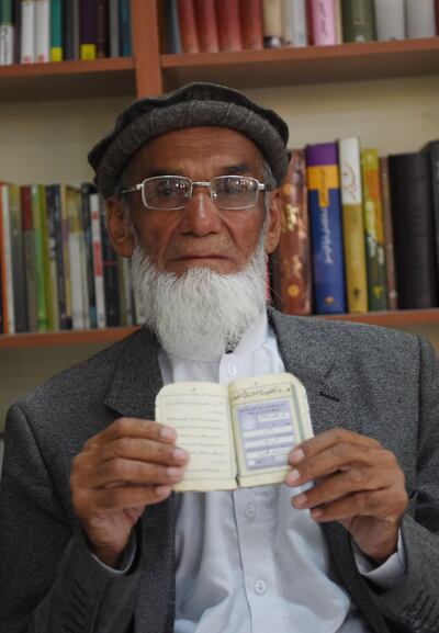Abdul Karim, 85, poses for a picture as he holds his id card or Tazkira registered to vote in the upcoming parliamentary election, in Kabul. AFP