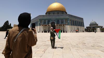 A girl poses for a picture with the Palestinian flag in front of the Dome of the Rock mosque inside Jerusalem's Al Aqsa Mosque complex, on May 27. AFP