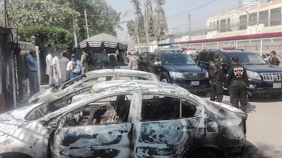 Pakistani security personnel stand next to burnt vehicles in front of the Chinese consulate in Karachi. AFP