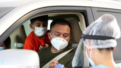A healthcare worker performs a coronavirus test at a drive-through centre in Abu Dhabi. Chris Whiteoak / The National