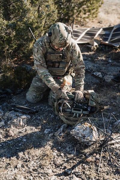 A soldier pulling power from solar panels to recharge radio batteries. Photo: Galvion