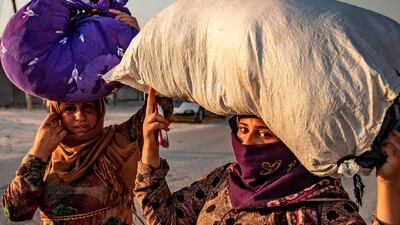 Civilians carry their belongings over their head as they flee amid Turkish bombardment on Syria's northeastern town of Ras Al Ain. AFP
