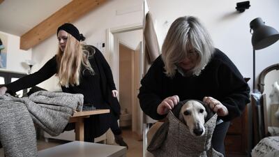 Giovanna Temellini (L) adjusts an outfit on a greyhound dog in her workshop in Milan. AFP