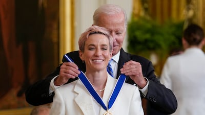 Mr Biden awards football star and activist Megan Rapinoe at the White House. AP