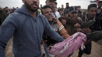 Palestinian protesters carry a wounded man who was shot by Israeli troops during a demonstration near the Gaza Strip border with Israel in eastern Gaza City on March 30, 2018. Khalil Hamra / AP Photo