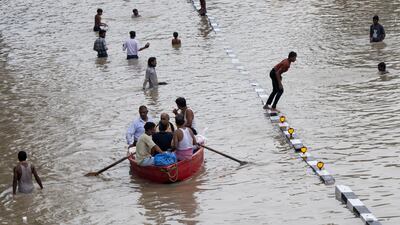 People travel by boat on a flooded road in New Delhi. Bloomberg