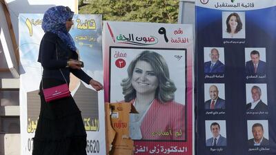A Jordanian woman passes election campaign posters in Amman, Jordan (EPA/JAMAL NASRALLAH)