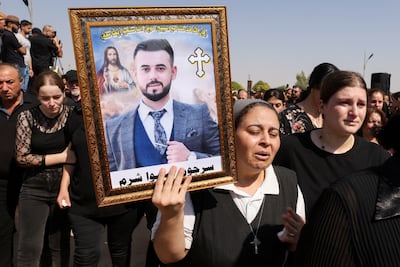 A mourner carries a portrait of a victim during the funeral. Reuters