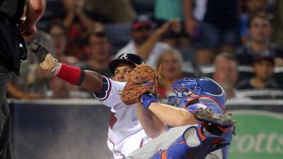 Emilio Bonifacio of the Atlanta Braves, centre left, is tagged out by New York Mets catcher Travis d’Arnaud, centre right, during their baseball game. John Bazemore / AP Photo