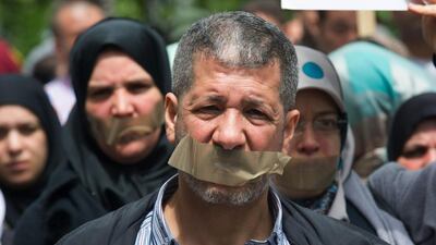 Protesters with tape over their mouths outside a police station in Berlin, Germany 21 on June 2015. About 60 people are calling for the release of Al Jazeera journalist Ahmed Mansour who was arrested at the Berlin-Tegel Airport a day earlier when he tried to fly to Doha, Qatar. Paul Zinken/EPA