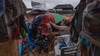 Beachgoers shelter from the rain outside their beach hut in Broadstairs, Kent. Getty Images