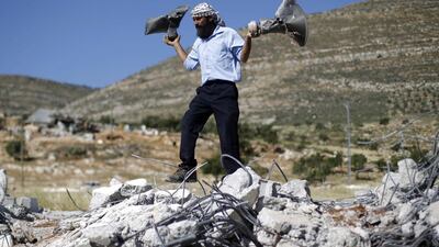 A Palestinian man holds damaged loudspeakers belonging to a mosque after it was demolished by Israeli bulldozers in Khirbet Al Taweel village near the West Bank City of Nablus on April 29. Mohamad Torokman / Reuters