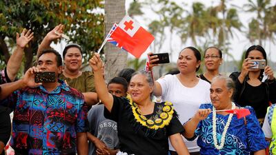 People wave as the royal motorcade carrying Meghan, Duchess of Sussex, and Britain's Prince Harry, Duke of Sussex, travels in Tonga. Reuters