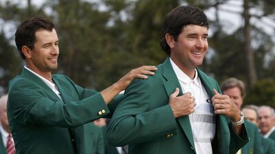 Masters champion Bubba Watson, right, of the U.S. is helped with his traditional green jacket by last year's champion Adam Scott of Australia after the final round of the Masters golf tournament at the Augusta National Golf Club in Augusta, Georgia on Sunday, April 13, 2014. REUTERS/Jim Young