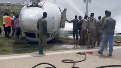 Firefighters spray water on a plane that flipped over after a crash landing, in Mogadishu, Somalia, July 18, 2022, in this screen grab obtained from a social media video obtained by Reuters. THIS IMAGE HAS BEEN SUPPLIED BY A THIRD PARTY NO RESALES. NO ARCHIVES