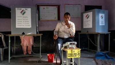 A polling official looks on as a woman casts her vote in Dharamshala. AP Photo