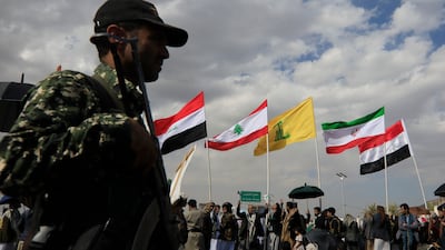 A Houthi soldier stands guard during a protest in Sanaa with the flags of Iraq, Lebanon, Hezbollah, Iran and Yemen behind him. EPA