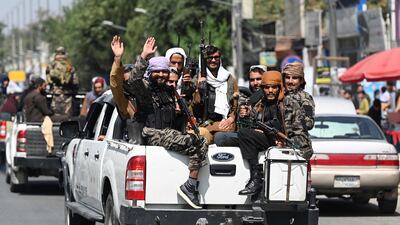 Taliban fighters wave as they patrol in a convoy along a street in Kabul. AFP
