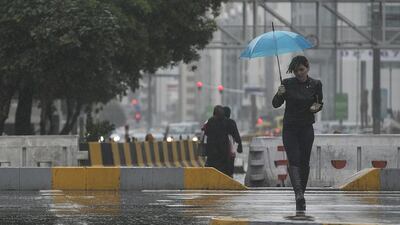 A tad wet … the rare sight of an umbrella on the gloomy streets of Abu Dhabi on Sunday. Mona Al Marzooqi / The National