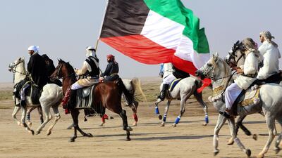 Members of the Kuwaiti knights team carry a national flag as they perform with their horses on the sea side, 70 kms west of the capital Kuwait City on December 11, 2020. AFP