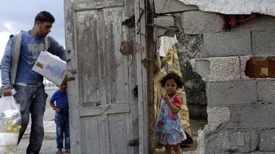 A girl stands behind a hole in a wall of her house in the Al-Shati refugee camp in Gaza City. Mohammed Abed / AFP