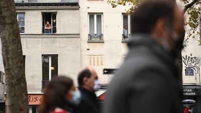 A woman looks out from her window as tributes are paid outside La Belle Equipe bar in Paris. AFP