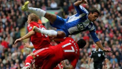 Wigan's Amr Zaki flys through the air and into Liverpool's Dirk Kuyt and Alvaro Arbeloa in his side's 3-2 defeat on Saturday.