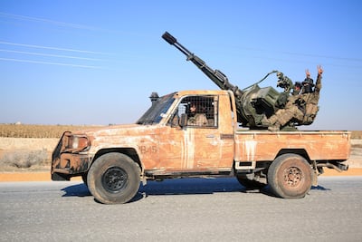 Anti-government fighters ride military vehicles as they drive along a road in the eastern part of Aleppo province.AFP