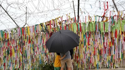 A family hangs a ribbon wishing for reunification of the two Koreas at the Imjingak Pavilion, in Paju, South Korea. Ahn Young-joon / AP Photo
