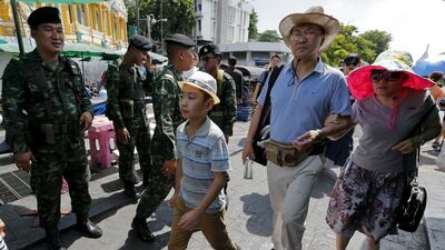 Military personnel stand guard as tourists walk past near the Grand Palace in Bangkok. Chaiwat Subprasom / Reuters