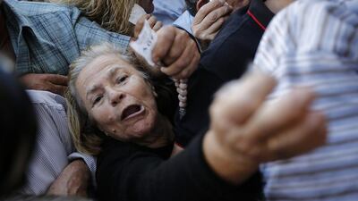 Pensioners wave ticket numbers as they try to get inside a National Bank of Greece SA bank branch to collect their pensions in Athens, Greece, on Wednesday, July 1, 2015. Simon Dawson/Bloomberg