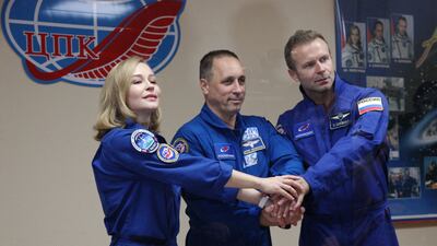 This handout photo taken and released on October 4, 2021 by the Russian Space Agency Roscosmos shows crew members, cosmonaut Anton Shkaplerov (C), actress Yulia Peresild (L) and film director Klim Shipenko, shaking hands behind a glass wall during a news conference ahead of the expedition to the International Space Station (ISS) at the Baikonur Cosmodrome, Kazakhstan. - Roscosmos is dispatching the 36-year-old screen star Yulia Peresild along with director Klim Shipenko, 38, and cosmonaut Anton Shkaplerov in the race against time to beat a parallel Hollywood project led by actor Tom Cruise. The launch to ISS is scheduled for October 5, 2021. (Photo by Andrey SHELEPIN / GCTC / Russian space agency Roscosmos / AFP) / RESTRICTED TO EDITORIAL USE - MANDATORY CREDIT "AFP PHOTO / Russian space agency Roscosmos / Andrey SHELEPIN" - NO MARKETING - NO ADVERTISING CAMPAIGNS - DISTRIBUTED AS A SERVICE TO CLIENTS