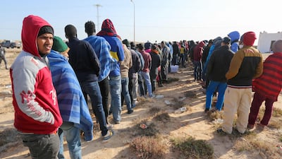 Migrants caught by Tunisia's national guard during an attempted crossing of the Mediterranean queue for food rations at the port of El Ketef in southern Tunisia, near the border with Libya, on November 27, 2021. AFP