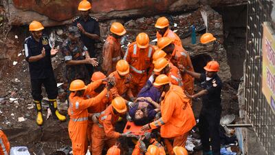 Rescue workers cheer as a survivor is brought out alive on a stretcher from the debris of a collapsed building in Mumbai. AFP
