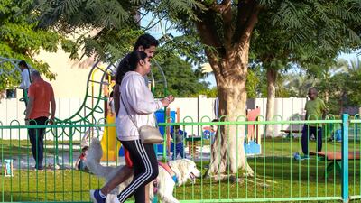 A couple takes their dog for a walk. Al Reef is a pet friendly community, which is a big draw for many.