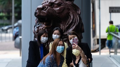 People take a selfie photograph with a statue of a lion in front of the HSBC Holdings Plc headquarters building in Hong Kong, China. Bloomberg