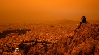 A couple sit on Tourkovounia hill, as southerly winds carry waves of Saharan dust, in Athens. AFP