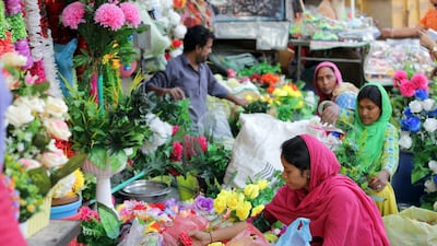 Indian vendors prepare artificial flower pots for sale at a roadside shop on the eve of Diwali festival in Amritsar, India. EPA