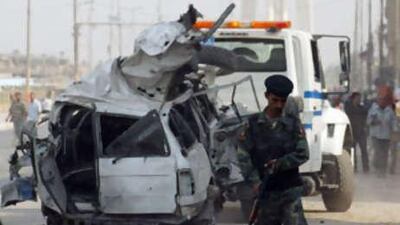An Iraqi soldier secures the area as a truck removes a destroyed car on Oct 23 2008 where a suicide bomber slammed into the convoy of Iraq's labour minister, killing at least eleven people.