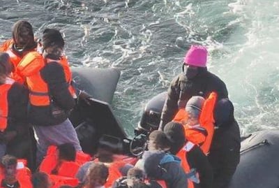Sudanese national Alnour Ali, wearing a pink hat, piloting a small boat on the English Channel. CPS/PA