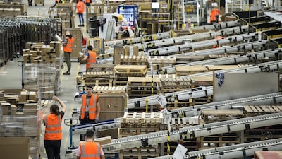 Workers prepare customer orders for dispatch as they work around goods stored inside an Amazon.co.uk fulfillment centre in Peterborough. AFP