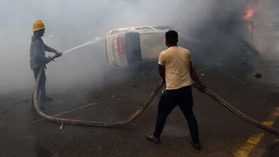 Indian firemen put out a burning vehicle belonging to a member of the media. Altaf Qadri / AP Photo