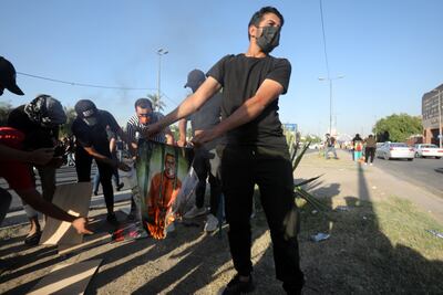 A demonstrator burns a picture of Iraqi Prime Minister Mustafa Al-Kadhimi during the protest on Saturday. EPA