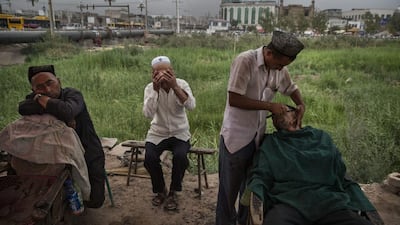 A Uighur barber shaves a customer in Xinjiang province's old Kashgar city before the Eid holiday on July 28, 2014. Kevin Frayer / Getty Images