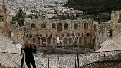A tourist takes pictures in front of the ancient theatre of Herod Atticus at Acropolis hill. REUTERS/John Kolesidis