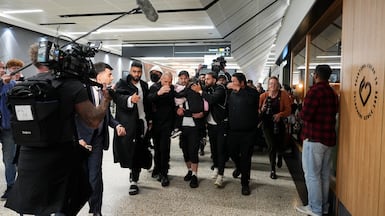 A group of supporters shield women and children with links to ISIS as they arrive at Melbourne Airport. Getty Images