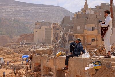 A survivor sits on the rubble of a destroyed building in Libya's eastern city of Derna. AFP.