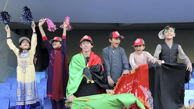 Kids wave the flag during the game between Kandahar Knights and Balkh Legends in the Afghanistan Premier League.